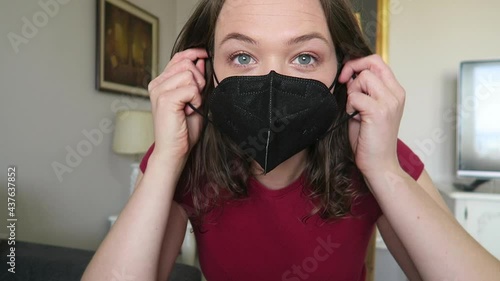 Pretty girl trying on black face mask looking at herself