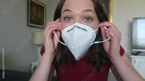 Pretty girl trying on white face mask looking at herself