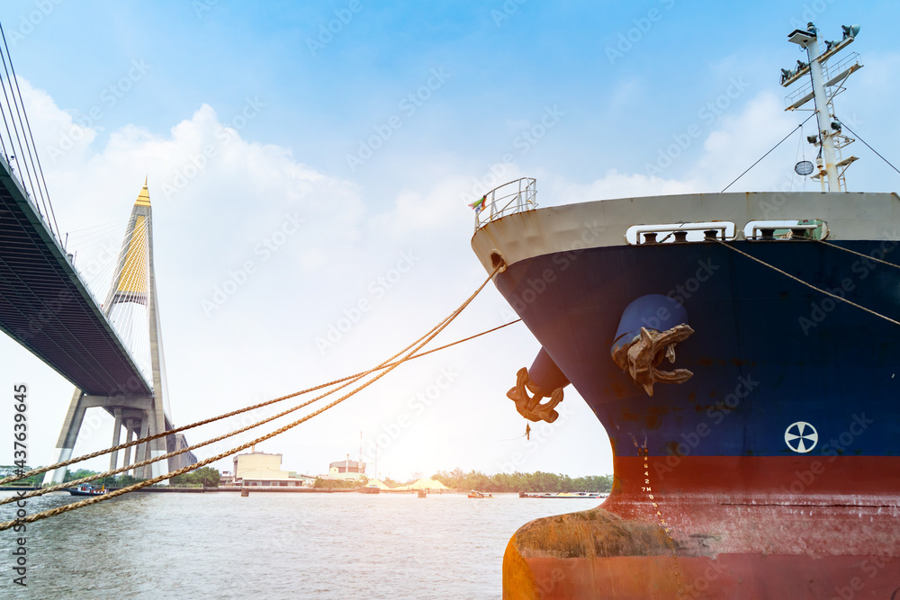 Fototapeta premium Cargo ships or break-bulk carrier. Logistics and transportation of container with Bhumibol bridge in shipyard,Thailand,with sunlight at port,logistic import export and transport industry.