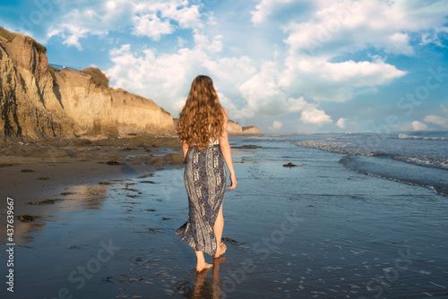 Back view woman with long hair walking on beautiful  southern california beach