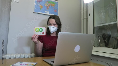 Pretty young woman teaching English online wearing a white face mask. Distance learning concept.
