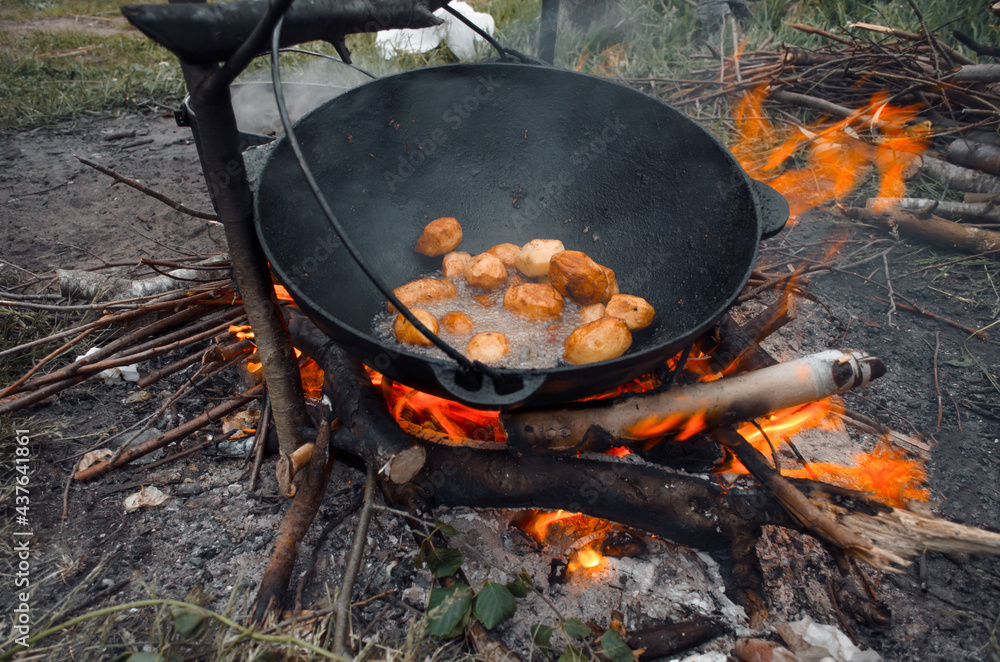 Outdoor picnic. Cooking in a hike in nature, fried potatoes over a fire in a pot. Outdoor picnic. Cooking in a hike in nature, fried potatoes over a fire in a pot.