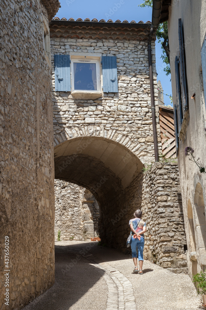 Femme touriste montant une ruelle dans le vieux village de Marsanne et passant sous une maison en arceau