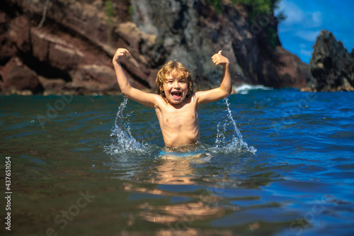 Amazed excited kid im sea water. Funny kid playing on beach. © Volodymyr