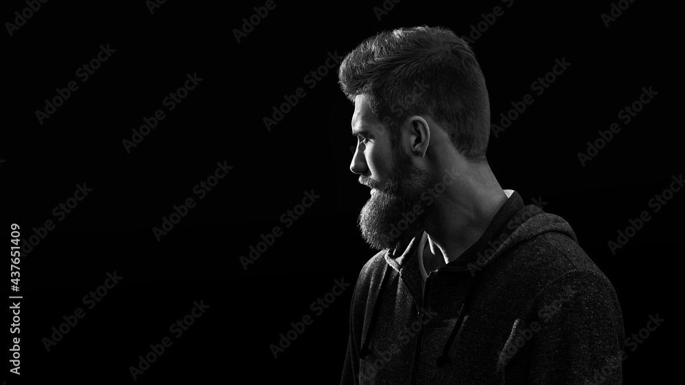Black and white shot of profile young handsome serious bearded man isolated on black background Black and white shot of profile young handsome serious bearded man isolated on black background