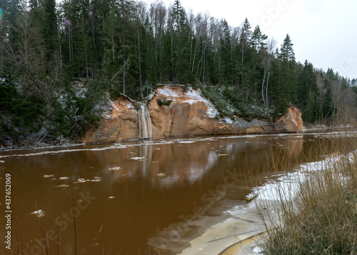 the river in early spring, sandstone outcrop, ice cubes in the water, river bank from the opposite bank, Erglu cliffs, river Gauja, Cesis, Latvia photo