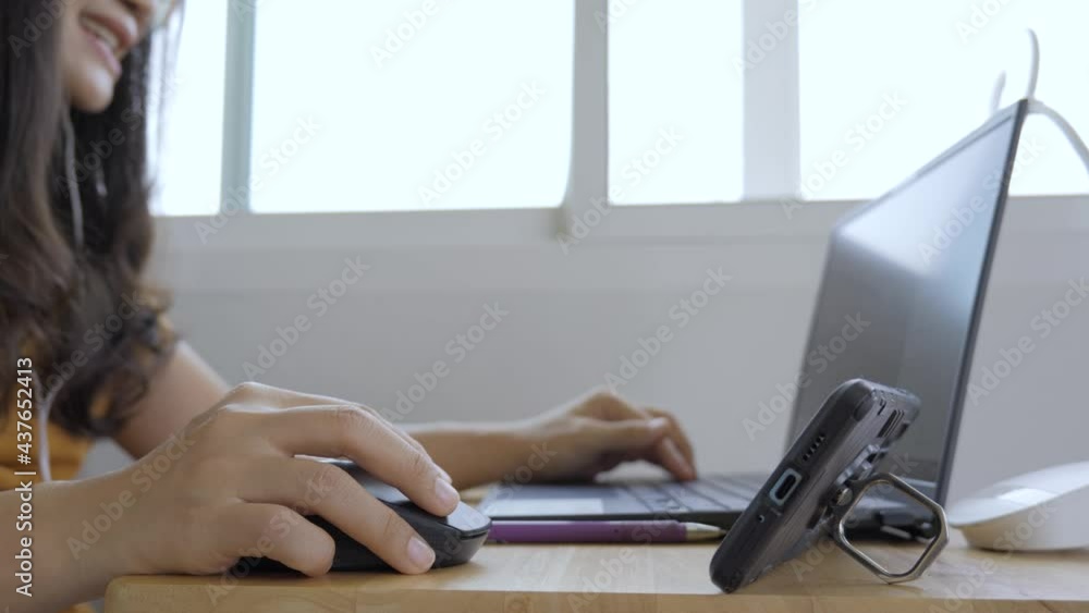 Asian woman teaching online class using a laptop computer and a mobile phone. Talking in a meeting to students as study from home. Asian woman teaching online class using a laptop computer and a mobile phone. Talking in a meeting to students as study from home.