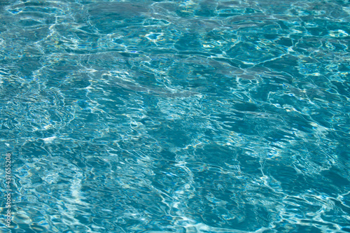 Blue pool water background. Blurred transparent clear calm water surface texture. Water waves in sunlight with copy space. © Volodymyr