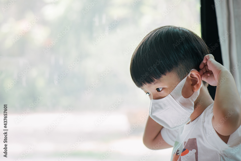 A boy try on wearing a mask by himself. He must learn how to protect himself from the virus before going outside.