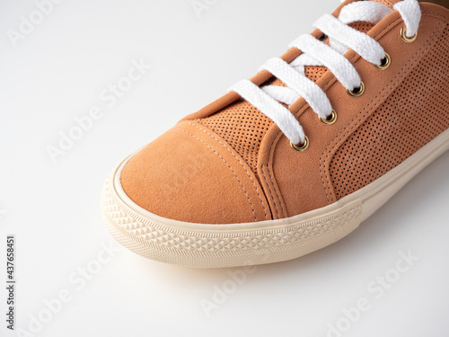 Close-up of new light brown sneakers with white laces on a white background. Nubuck suede leather. photo