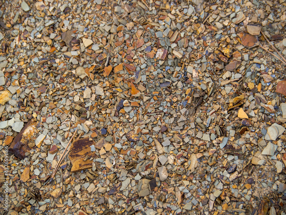 Texture brown gravelly soil. Background of rocky foothill lands. Various stones of brown and red color close-up. Texture brown gravelly soil. Background of rocky foothill lands. Various stones of brown and red color close-up.
