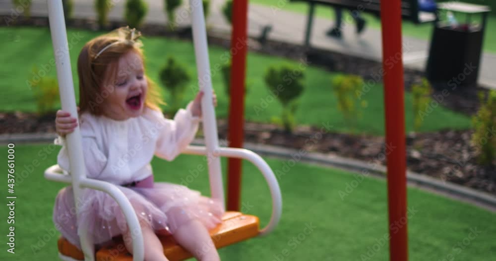 excited toddler baby girl having fun on swings at the playground excited toddler baby girl having fun on swings at the playground
