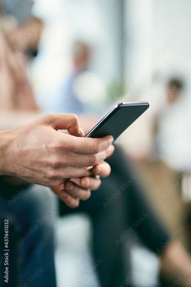 Close-up of businessman texting on smart phone in a waiting room.