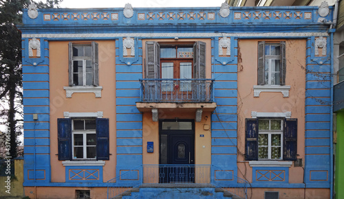 Old picturesque neoclassical building with beige walls and blue doors, windows and border. Impressive carved plaster designs. Komotini, Greece