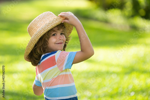Portrait of cheerful child in summer nature park. Cute joyful little boy kid. Close up portrait of funny little child boy in straw hat. Summer vacation.