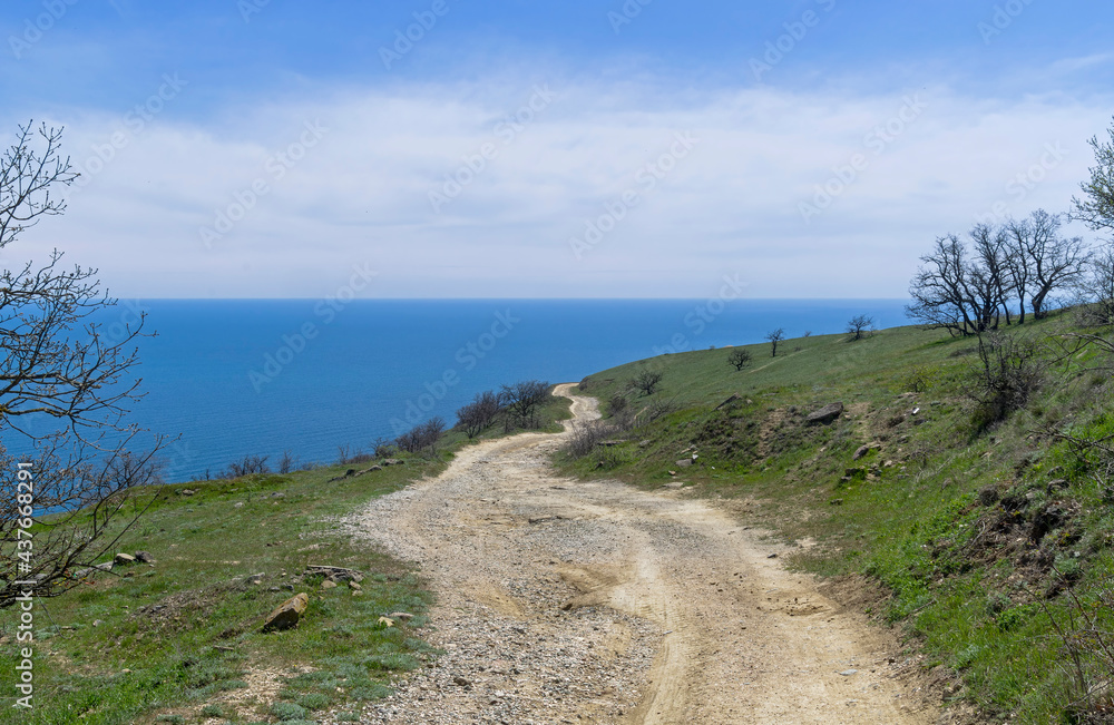 A dirt road running along a deserted mountainside on the seashore. A dirt road running along a deserted mountainside on the seashore.