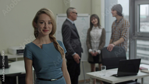 Attractive young woman standing in business office and smiling at camera