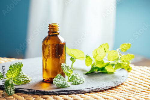 Mint or peppermint essential oil in a glass bottle used as an alternative medicine in aromatherapy or diluted in a carrier oil directly on skin