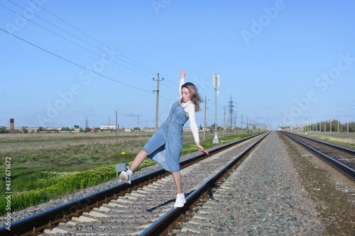 Young woman walks on railroad tracks. Falls out of balance.