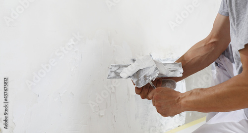 Obraz na płótnie Hands man plasterer construction worker at work with trowel, plastering a wall, closeup