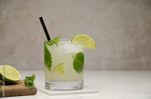 Mojito cocktail with lime, mint and ice in glass on gray background. Summer cold alcoholic non-alcoholic drinks, beverages and cocktails. Front view with copy space