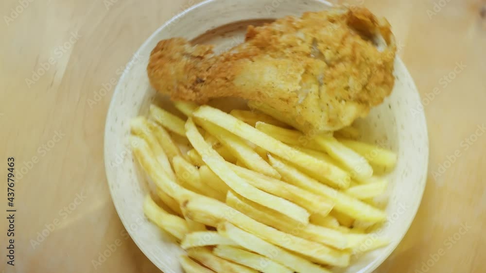 A dish of fried potatoes with fried chicken. Just a dish of fries and spiced chicken legs on a rotating plate. A dish of fried potatoes with fried chicken. Just a dish of fries and spiced chicken legs on a rotating plate.