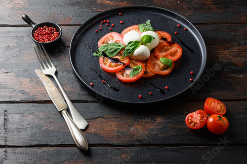 Caprese salad Tomato and mozzarella slices with basil leaves on olive wood  dark table