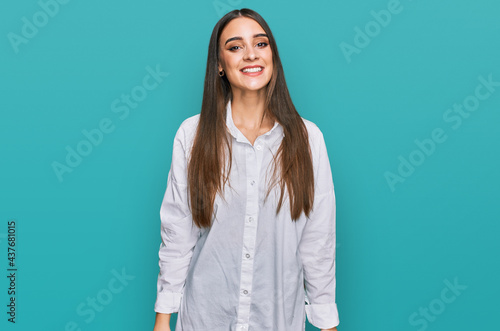 Young beautiful woman wearing casual white shirt looking positive and happy standing and smiling with a confident smile showing teeth