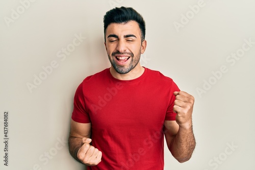 Young hispanic man wearing casual clothes celebrating surprised and amazed for success with arms raised and eyes closed