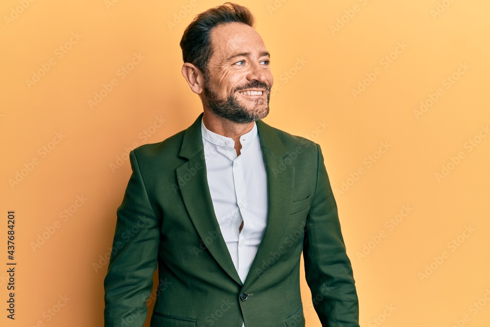 Middle age man wearing business suit looking away to side with smile on face, natural expression. laughing confident. Middle age man wearing business suit looking away to side with smile on face, natural expression. laughing confident.