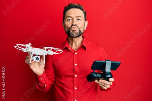 Middle age man using drone looking at the camera blowing a kiss being lovely and sexy. love expression.