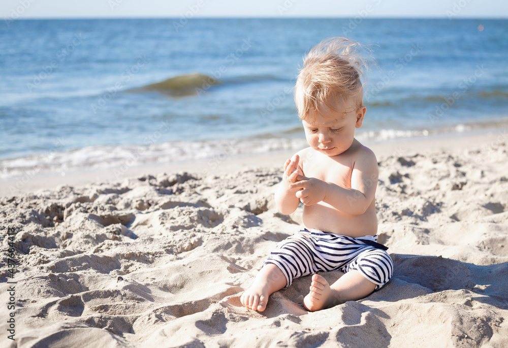 10 month old blond boy playing with sand on the beach 10 month old blond boy playing with sand on the beach