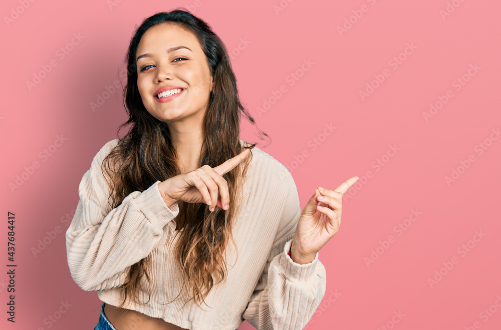 Young hispanic girl wearing casual clothes smiling and looking at the camera pointing with two hands and fingers to the side. Young hispanic girl wearing casual clothes smiling and looking at the camera pointing with two hands and fingers to the side.