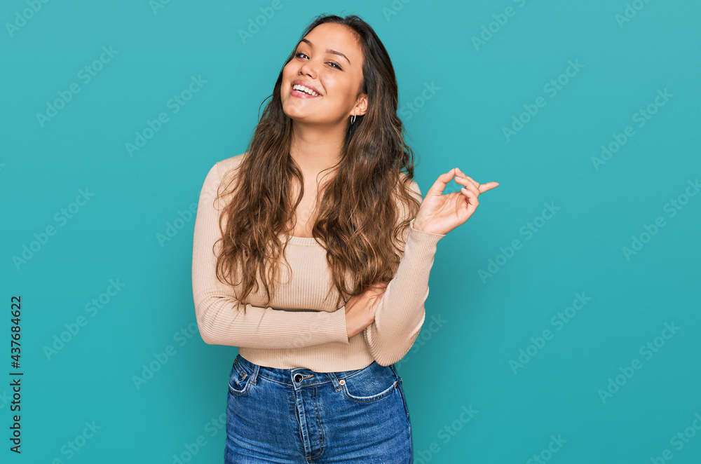 Young hispanic girl wearing casual clothes with a big smile on face, pointing with hand and finger to the side looking at the camera. Young hispanic girl wearing casual clothes with a big smile on face, pointing with hand and finger to the side looking at the camera.