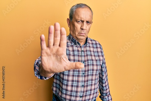 Handsome senior man with grey hair wearing casual shirt doing stop sing with palm of the hand. warning expression with negative and serious gesture on the face.