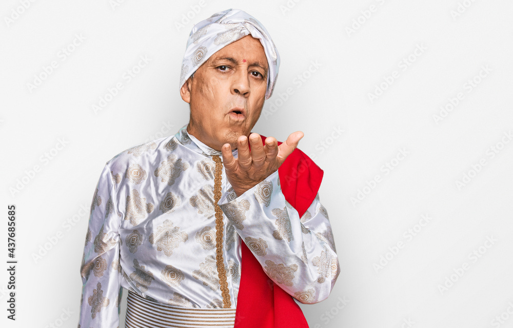 Senior hispanic man wearing tradition sherwani saree clothes looking at the camera blowing a kiss with hand on air being lovely and sexy. love expression. Senior hispanic man wearing tradition sherwani saree clothes looking at the camera blowing a kiss with hand on air being lovely and sexy. love expression.