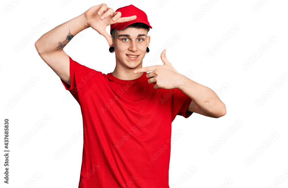Young caucasian boy with ears dilation wearing delivery uniform and cap smiling making frame with hands and fingers with happy face. creativity and photography concept.