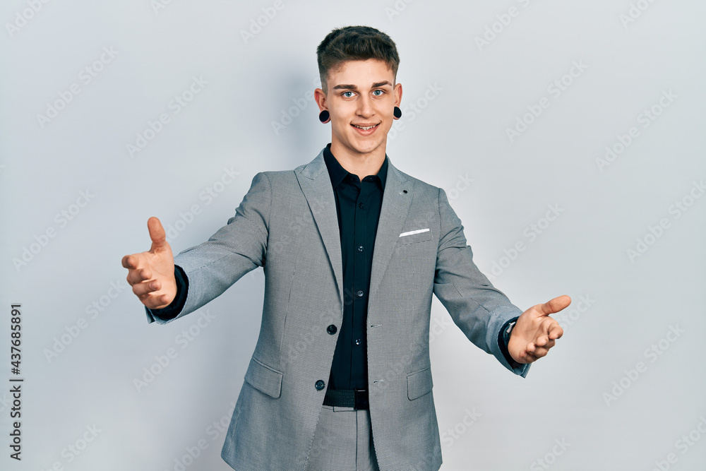 Young caucasian boy with ears dilation wearing business jacket looking at the camera smiling with open arms for hug. cheerful expression embracing happiness. Young caucasian boy with ears dilation wearing business jacket looking at the camera smiling with open arms for hug. cheerful expression embracing happiness.