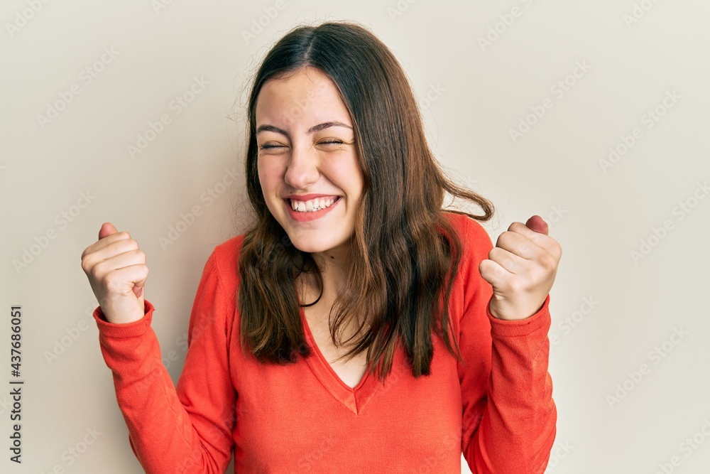 Young brunette woman wearing casual clothes very happy and excited doing winner gesture with arms raised, smiling and screaming for success. celebration concept. Young brunette woman wearing casual clothes very happy and excited doing winner gesture with arms raised, smiling and screaming for success. celebration concept.