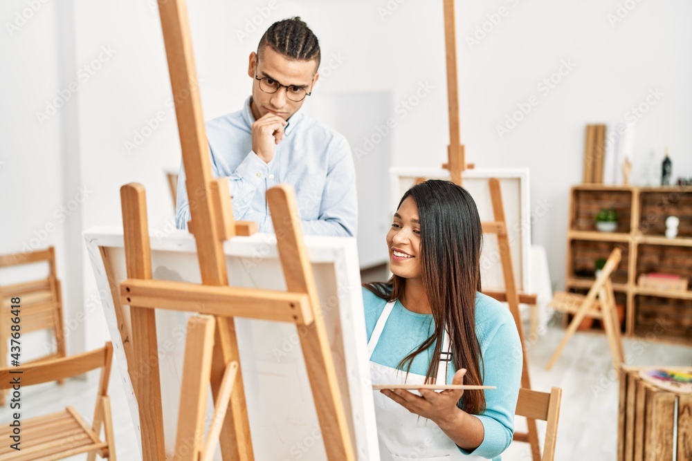 Young latin painter couple smiling happy painting at art studio Young latin painter couple smiling happy painting at art studio