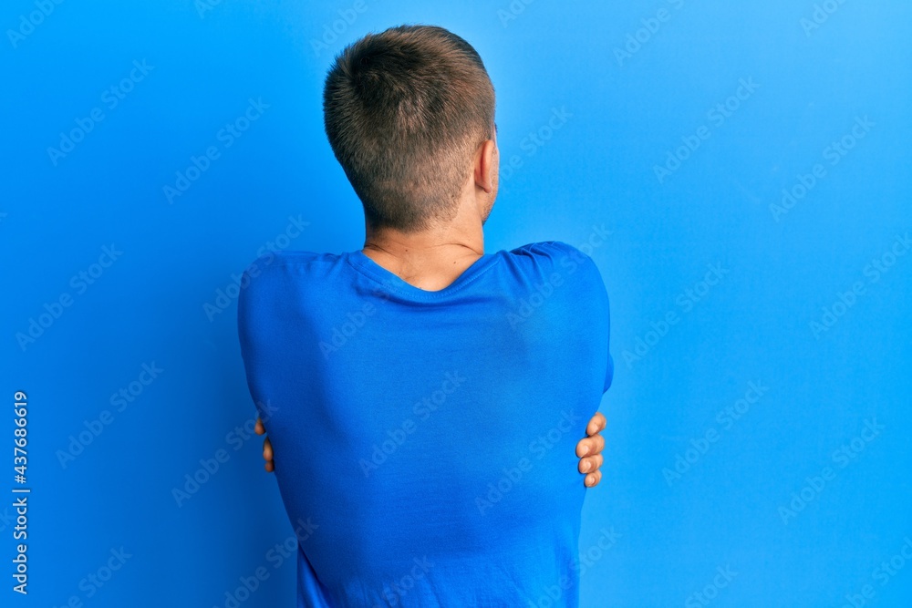 Young caucasian man wearing casual blue t shirt hugging oneself happy and positive from backwards. self love and self care Young caucasian man wearing casual blue t shirt hugging oneself happy and positive from backwards. self love and self care