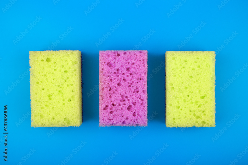 Colorful flat lay with with yellow andpurple sponges for house cleaning and dish washing on blue background. Concept of cleaning tools for home Colorful flat lay with with yellow andpurple sponges for house cleaning and dish washing on blue background. Concept of cleaning tools for home