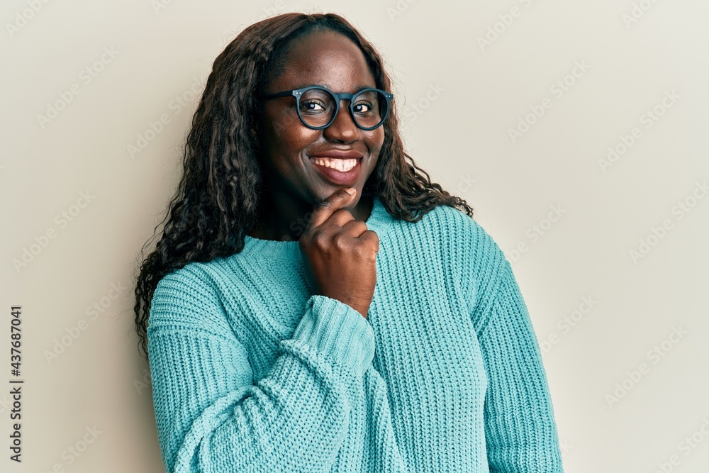 African young woman wearing casual clothes and glasses smiling looking confident at the camera with crossed arms and hand on chin. thinking positive. African young woman wearing casual clothes and glasses smiling looking confident at the camera with crossed arms and hand on chin. thinking positive.