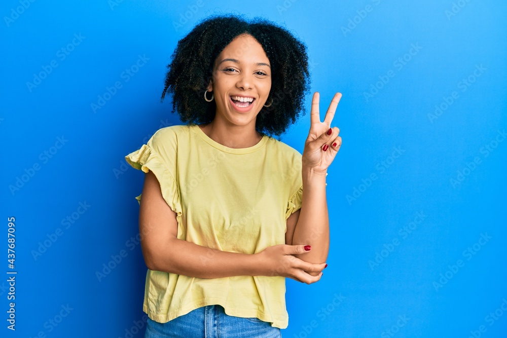Young african american girl wearing casual clothes smiling with happy face winking at the camera doing victory sign. number two. Young african american girl wearing casual clothes smiling with happy face winking at the camera doing victory sign. number two.
