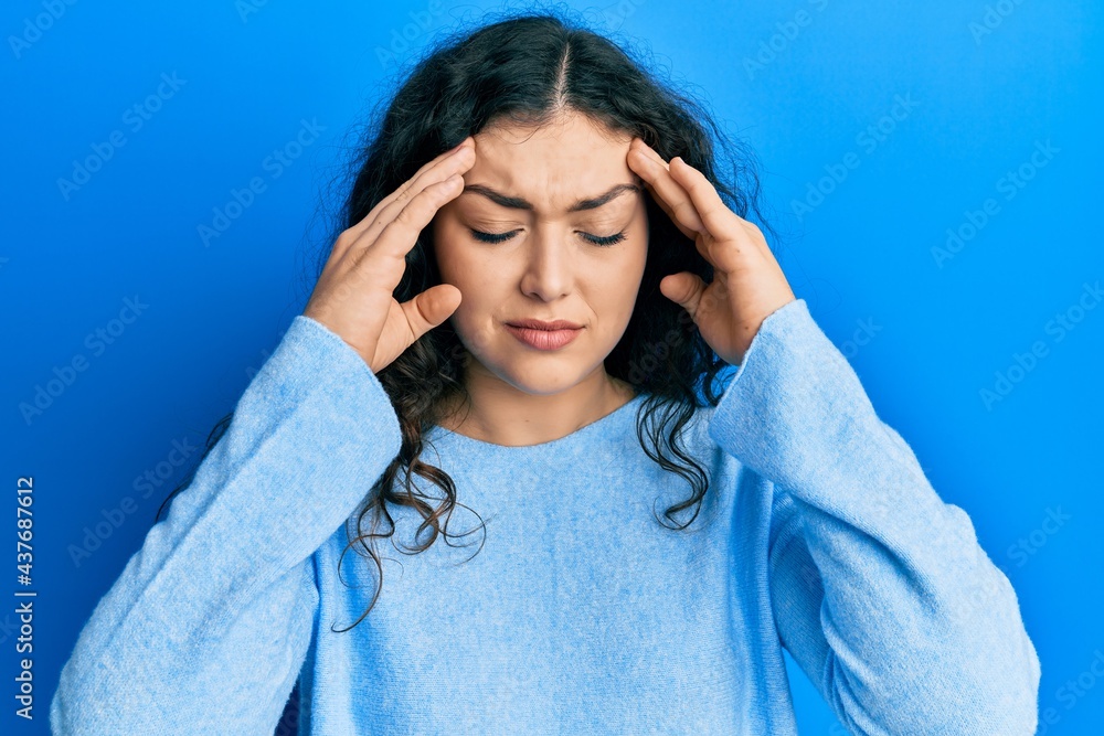 Young brunette woman with curly hair wearing casual clothes with hand on head for pain in head because stress. suffering migraine. Young brunette woman with curly hair wearing casual clothes with hand on head for pain in head because stress. suffering migraine.