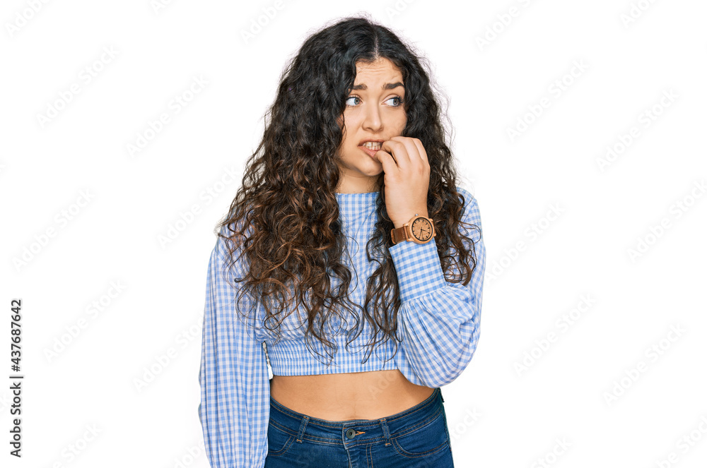 Young hispanic girl wearing casual clothes looking stressed and nervous with hands on mouth biting nails. anxiety problem. Young hispanic girl wearing casual clothes looking stressed and nervous with hands on mouth biting nails. anxiety problem.