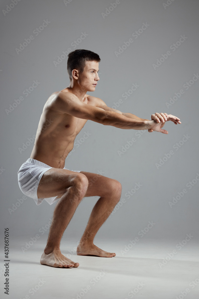 man doing sports squatting on gray background down man doing sports squatting on gray background down