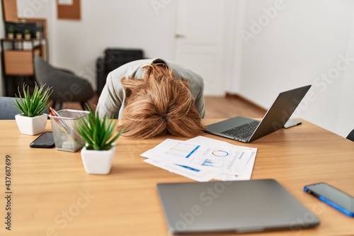 Middle age businesswoman overworked with head on desk at the office. photo