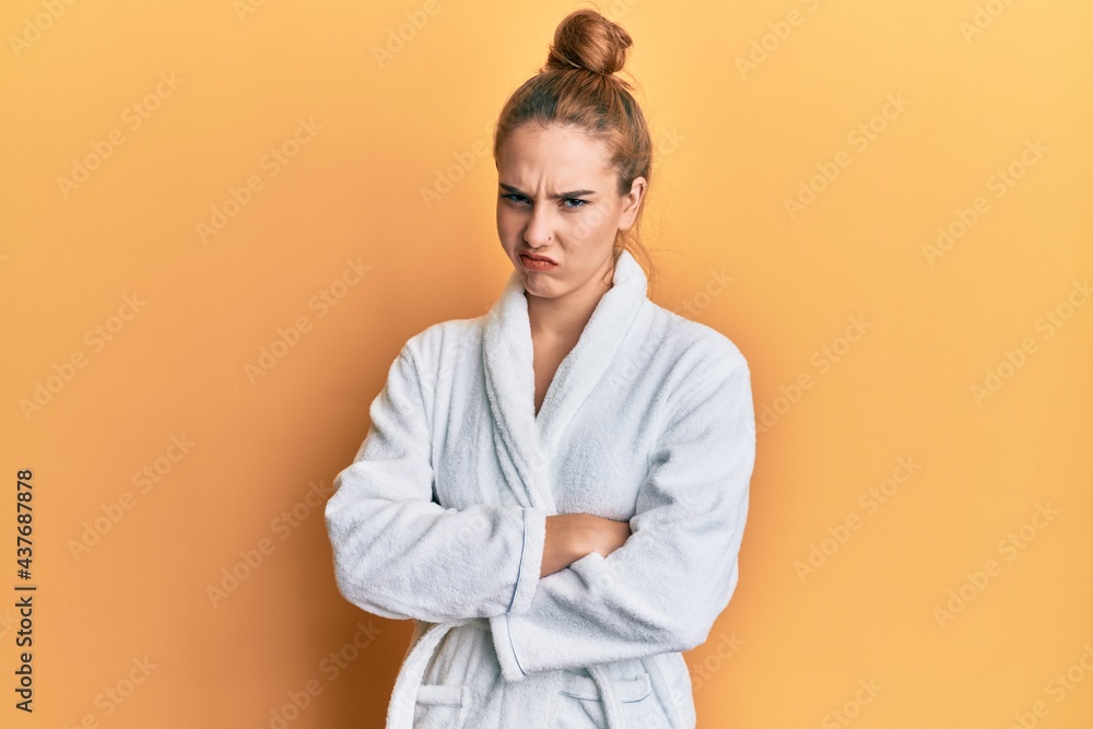 Young blonde woman wearing bathrobe skeptic and nervous, disapproving expression on face with crossed arms. negative person. Young blonde woman wearing bathrobe skeptic and nervous, disapproving expression on face with crossed arms. negative person.
