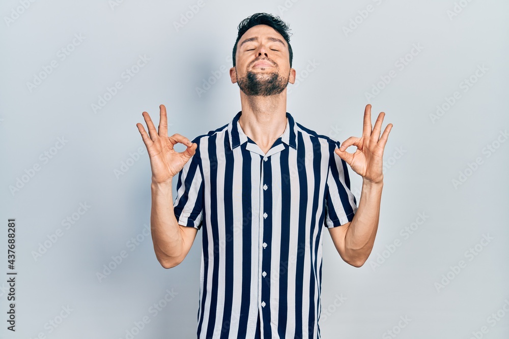 Young hispanic man wearing casual clothes relax and smiling with eyes closed doing meditation gesture with fingers. yoga concept. Young hispanic man wearing casual clothes relax and smiling with eyes closed doing meditation gesture with fingers. yoga concept.